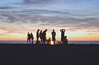 Junge Menschen mit Lagerfeuer am Strand